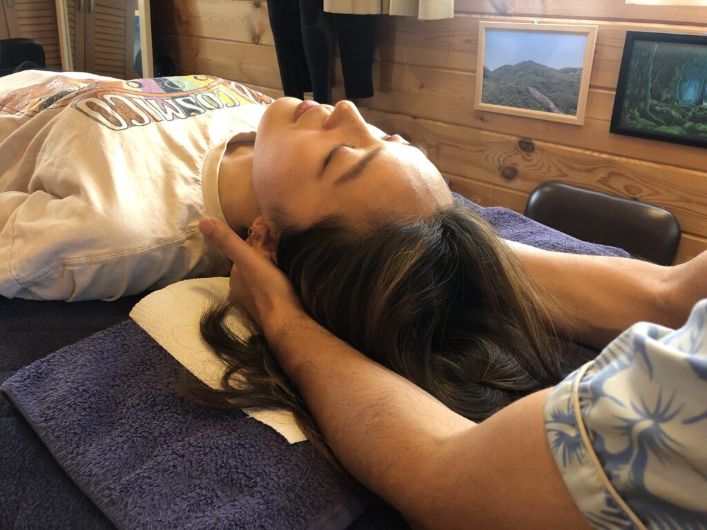 院内で頭と首にやさしく触れる施術風景